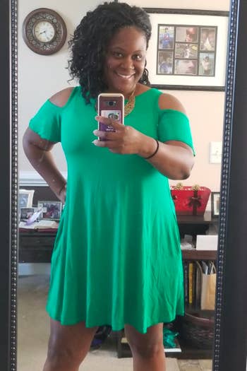 A reviewer wearing the short-sleeve, cold-shoulder dress in green