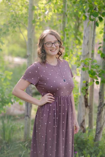 A reviewer wearing the dress in brown-red