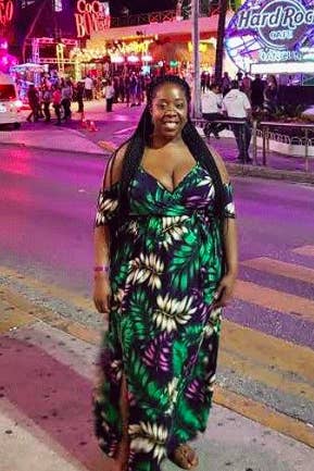 A reviewer wearing the dress in a black, white, green, and purple leaf print