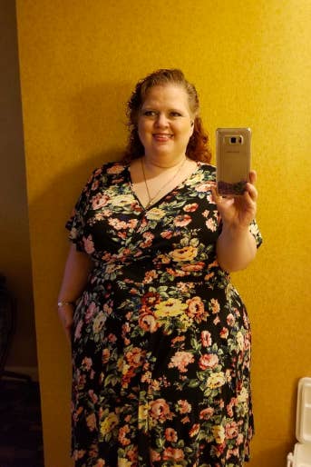 A reviewer wearing the short-sleeve dress in black with a floral print