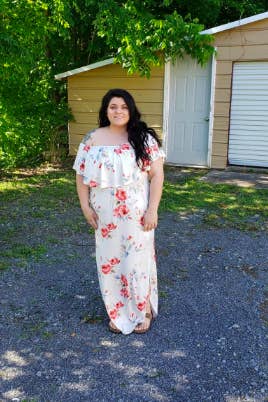 A reviewer wearing the dress in white with red flowers