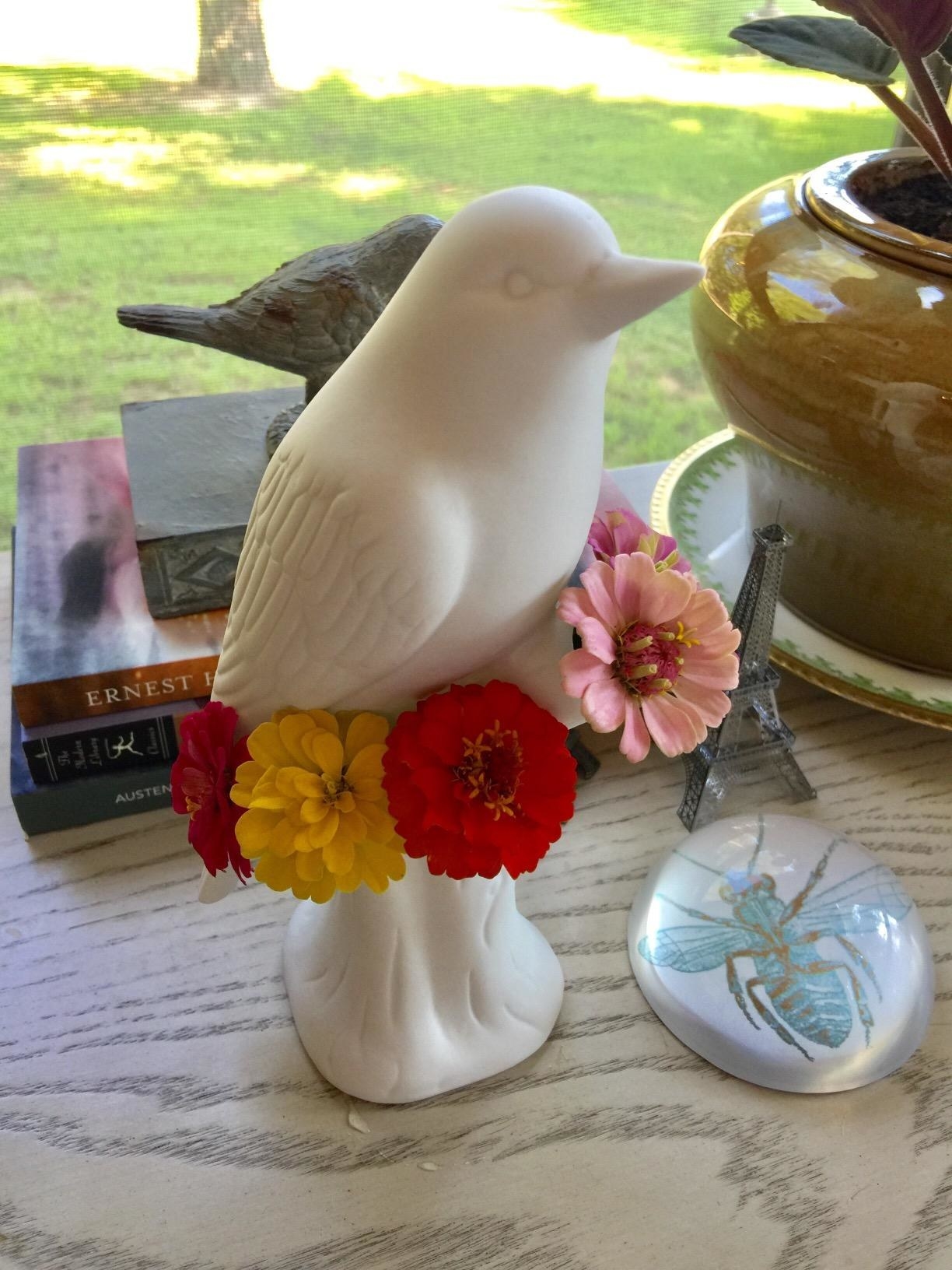 review photo of white bird on branch with flowers in the holes around the top of the branch area 