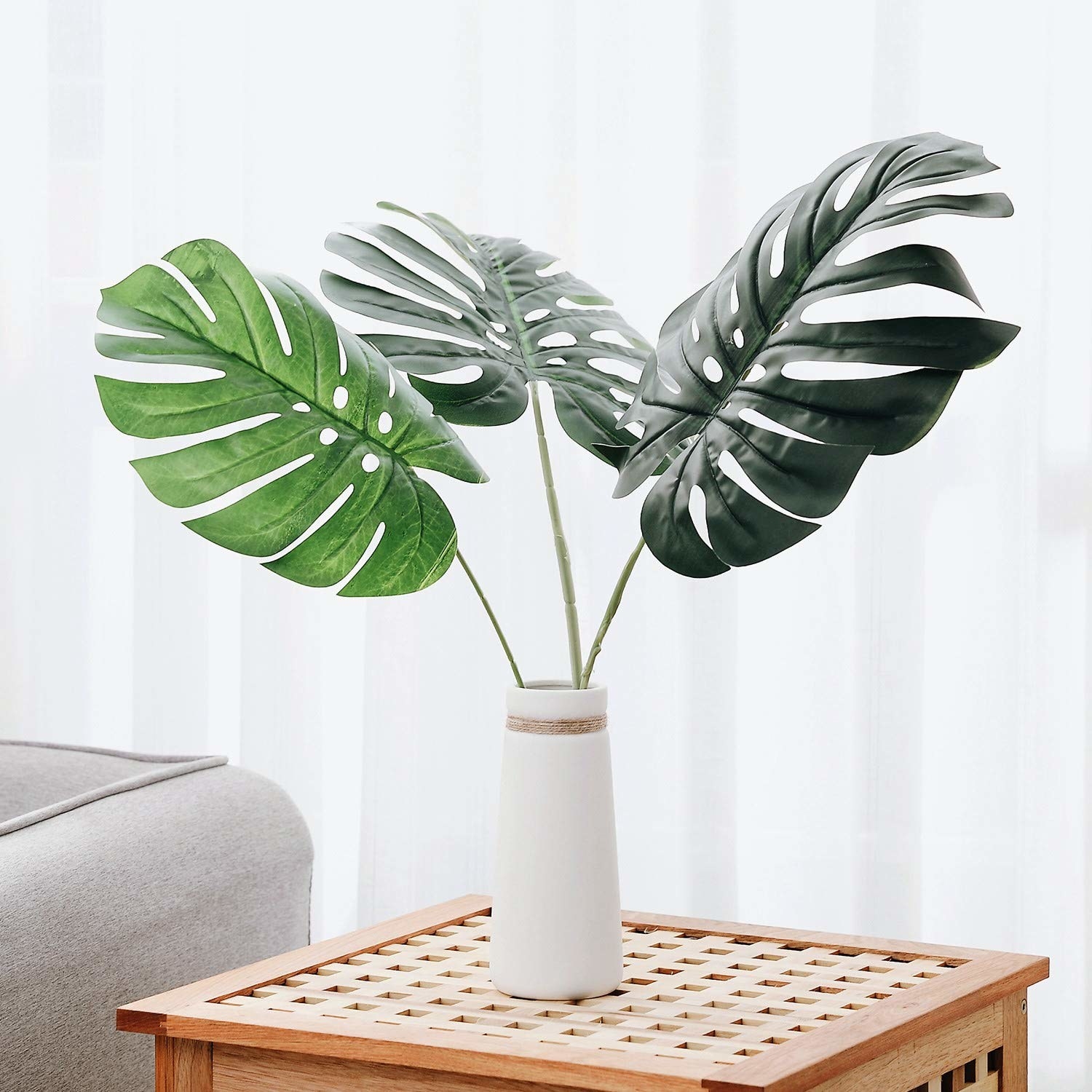 three large plastic monstera leaves in a vase