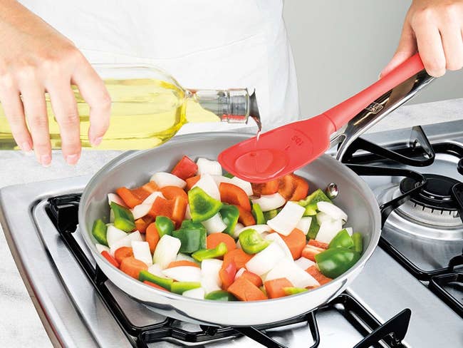 A model pouring oil into the spoon to measure it above a pan of stir-fry