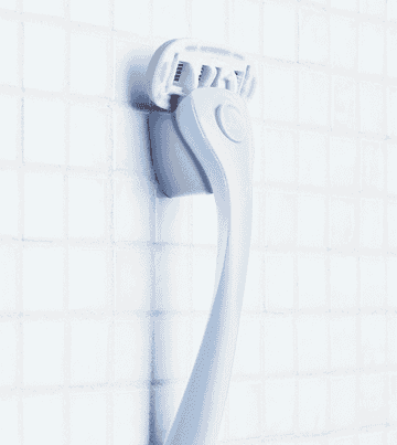 A gif of a person picking up their razor from the magnetic holder attached to the wall. The holder is mounted using gum paste.