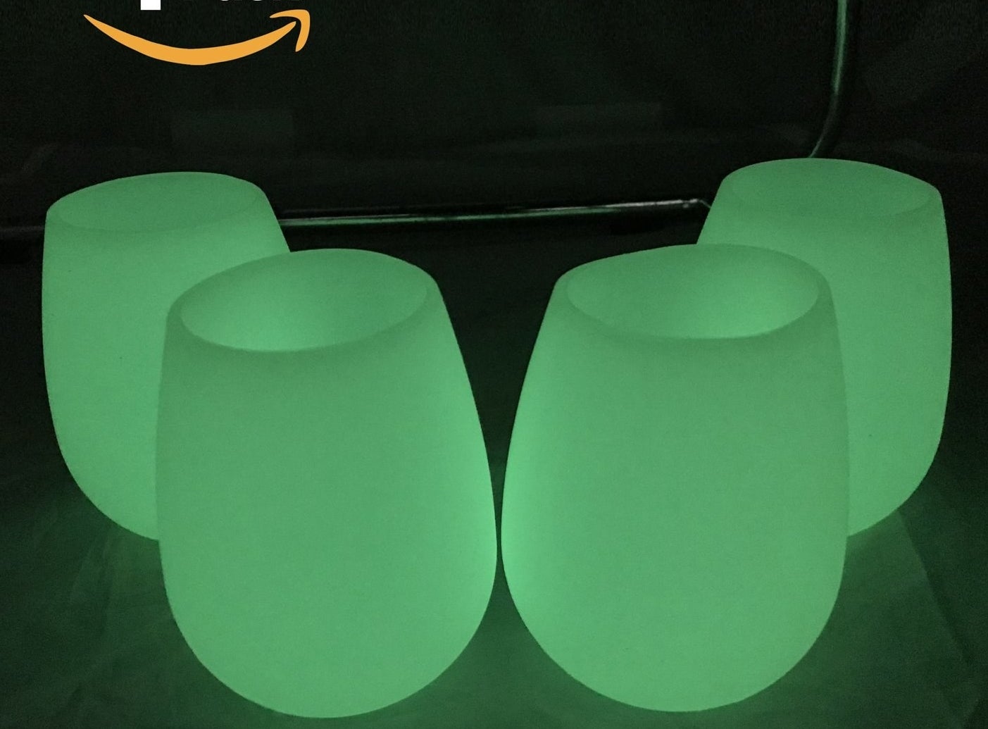 four stemless wineglasses glowing green in the dark