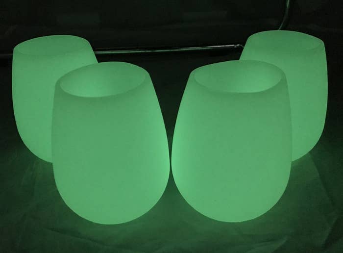 four stemless wineglasses glowing green in the dark