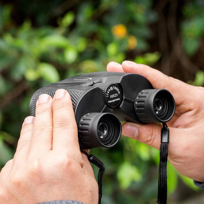 hands holding small black binoculars