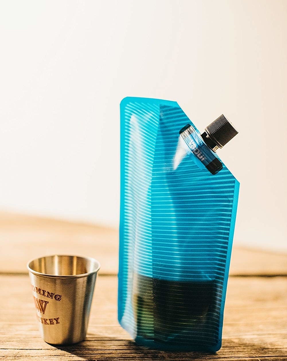 blue flexible flask with cap next to a shot glass
