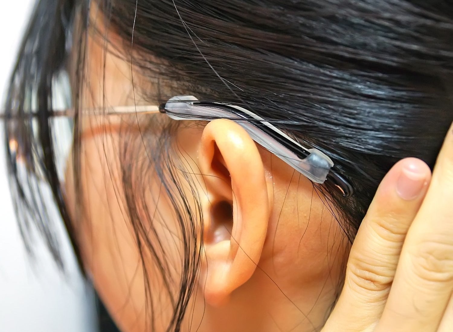 A model showing the glasses resting with the silicone cover on the back of their ear