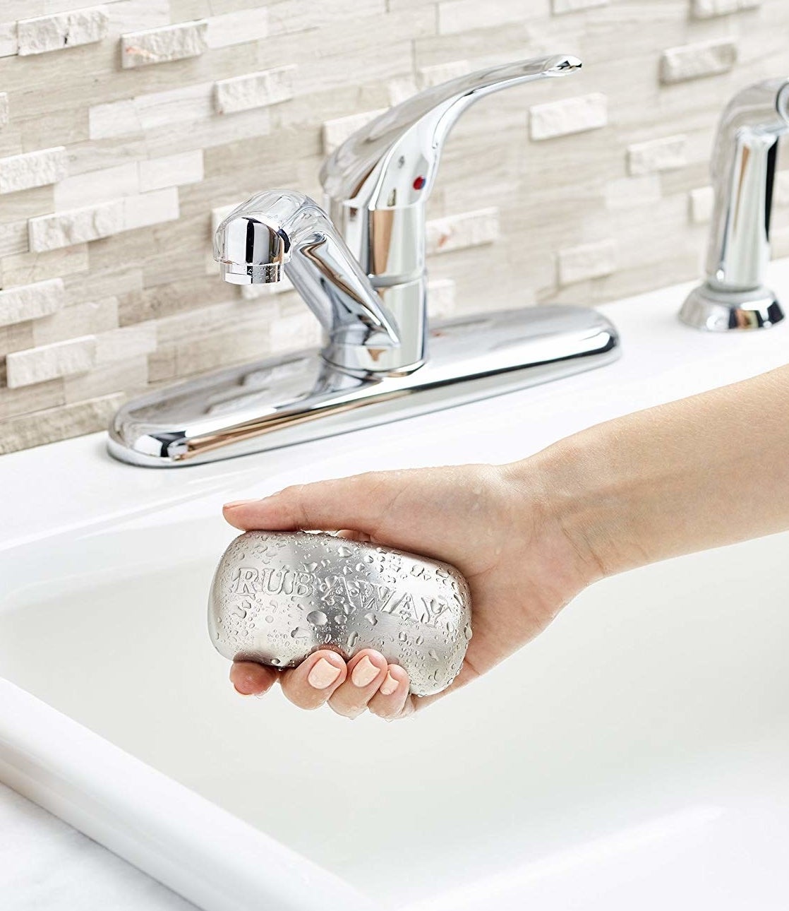 A model&#x27;s hand holding the bar in a sink