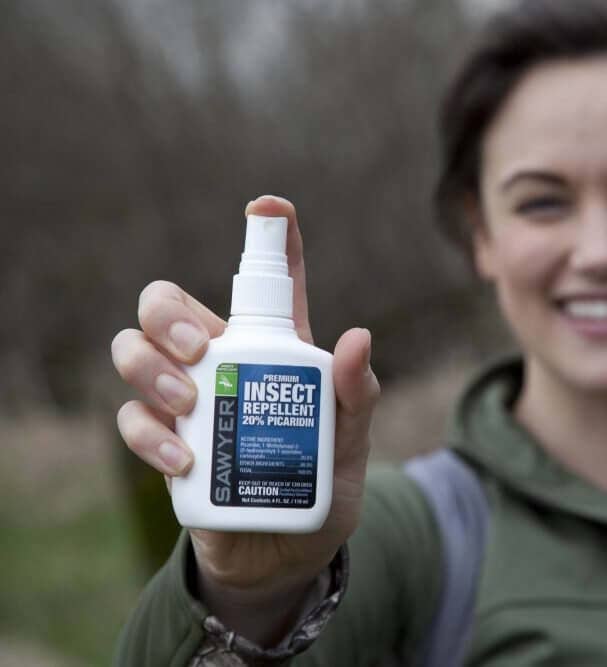 A model holding a medium bottle of the repellant 