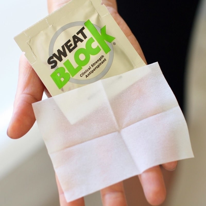 Product shot of a model holding a packet of Sweat Block with the small cloth out on their hand