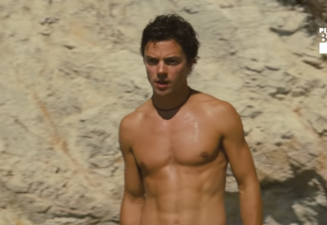 Shirtless Dominic Cooper from a beach scene