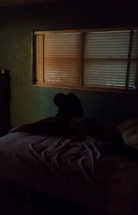 A lump on a bed looking like a hunched over person