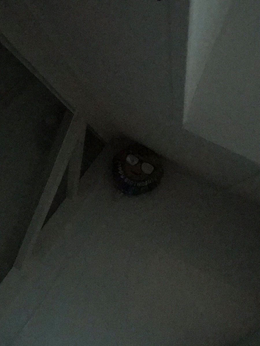 A balloon up in the corner of the room with a faint smiley face