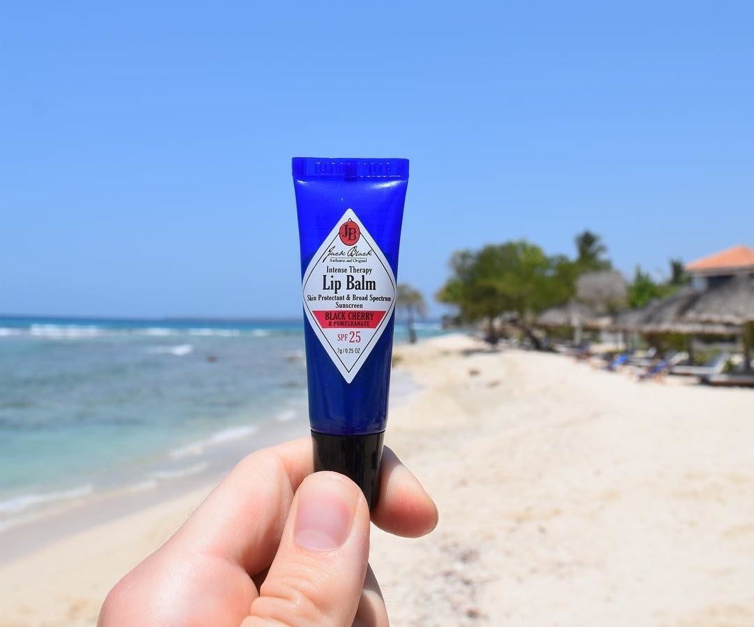 Model holding a small tube of Jack Black&#x27;s intense therapy lip balm