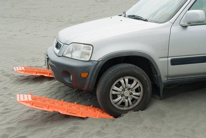 Car stuck in the sand being pulled up using traction mats