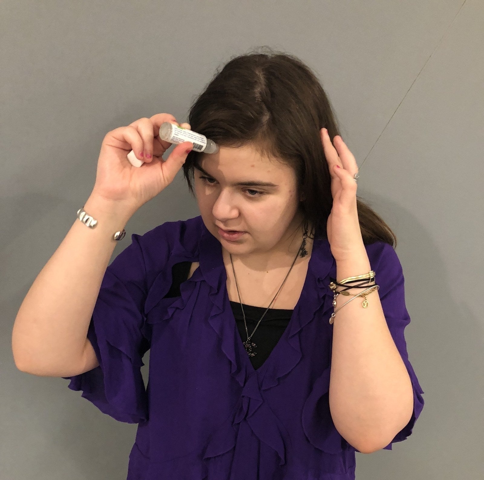 Writer showing how to apply the migraine stick to your forehead