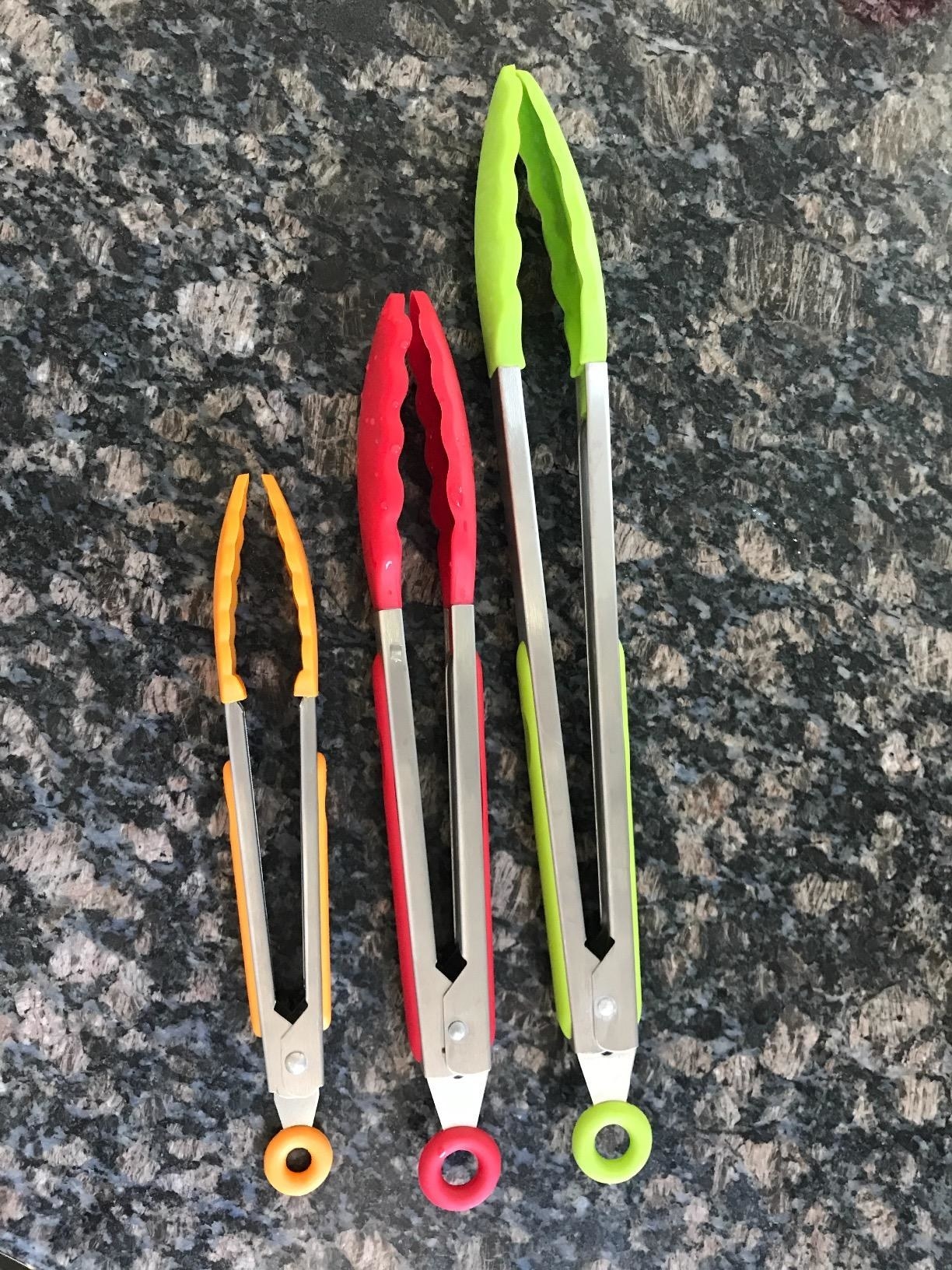 a reviewer&#x27;s small pair of orange tongs, medium pair of red tongs, and green pair of green tongs