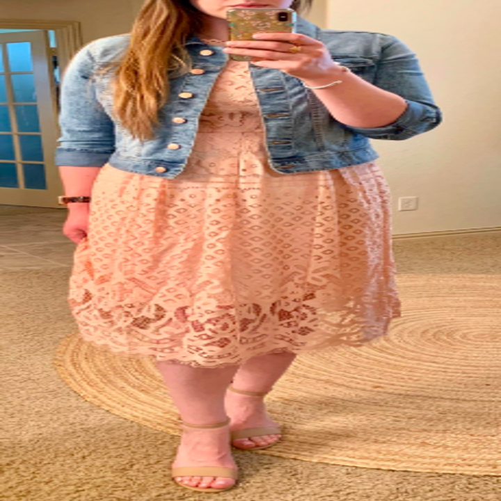 A reviewer wearing the dress in pale pink with a jean jacket