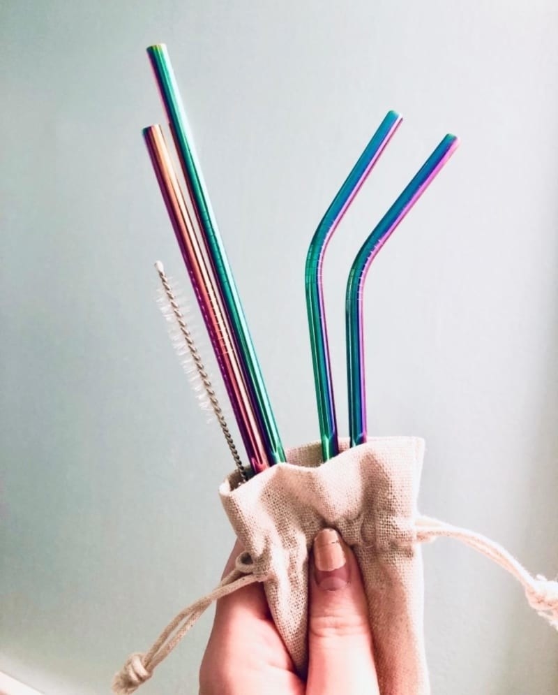 Reviewer image holding reusable straws. The straws have a rainbow metallic finish.