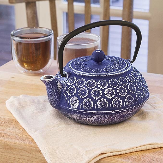 A blue teapot with floral details around the pot
