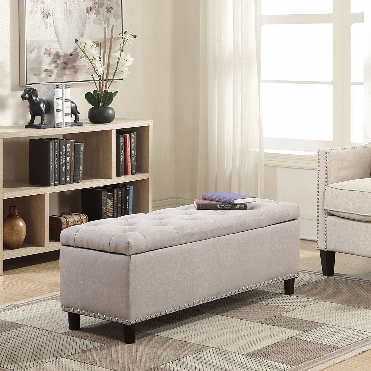 The grey fabric ottoman bench with silver studs on the bottom