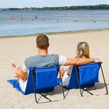 models lounging in two blue chairs at the beach