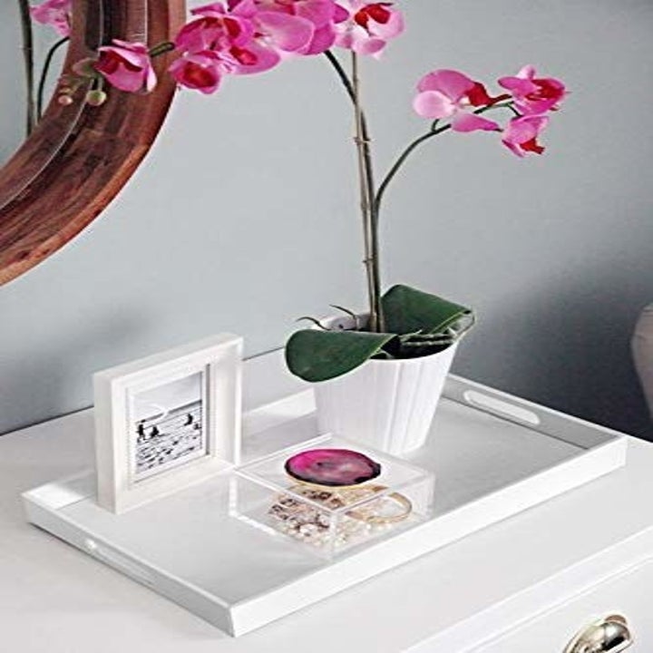 The decorative tray on a side table with decor neatly arranged on top of it