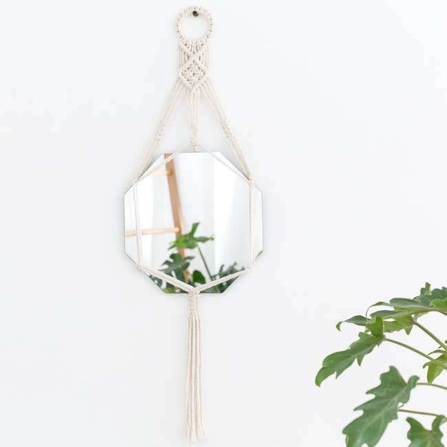 The macrame wall mirror hanging on a wall.