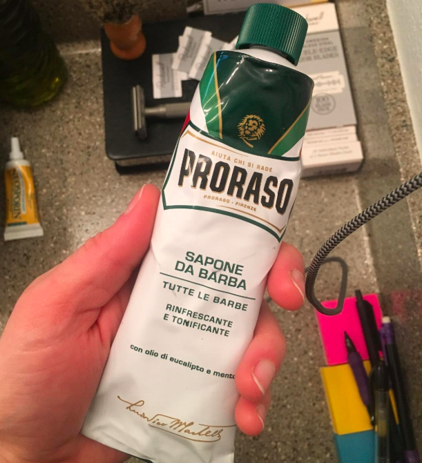 reviewer photo of hand holding the white shaving cream tube with green cap