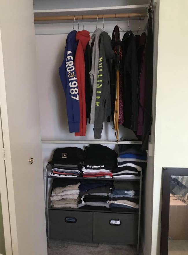 Reviewer photo of the organizer in a closet with lots of t-shirts folded and stacked on the two shelves