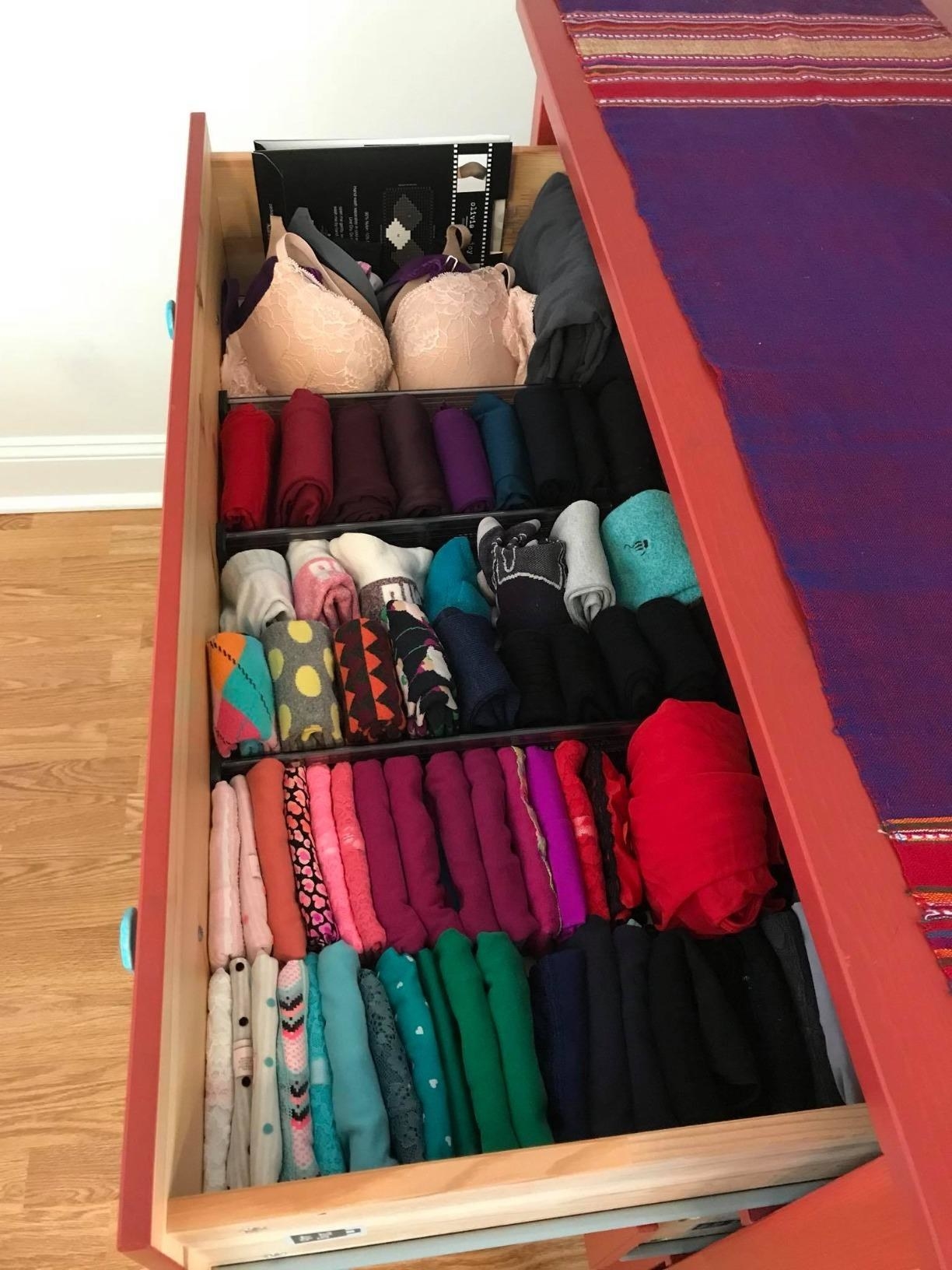 Reviewer photo of a drawer with the dividers in it with all the clothes perfectly folded and organized in between them 