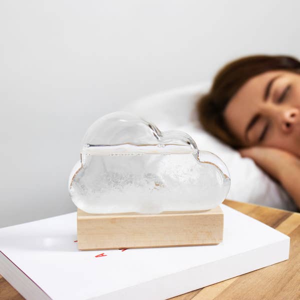 a glass cloud with water and crystals inside and a light wooden base