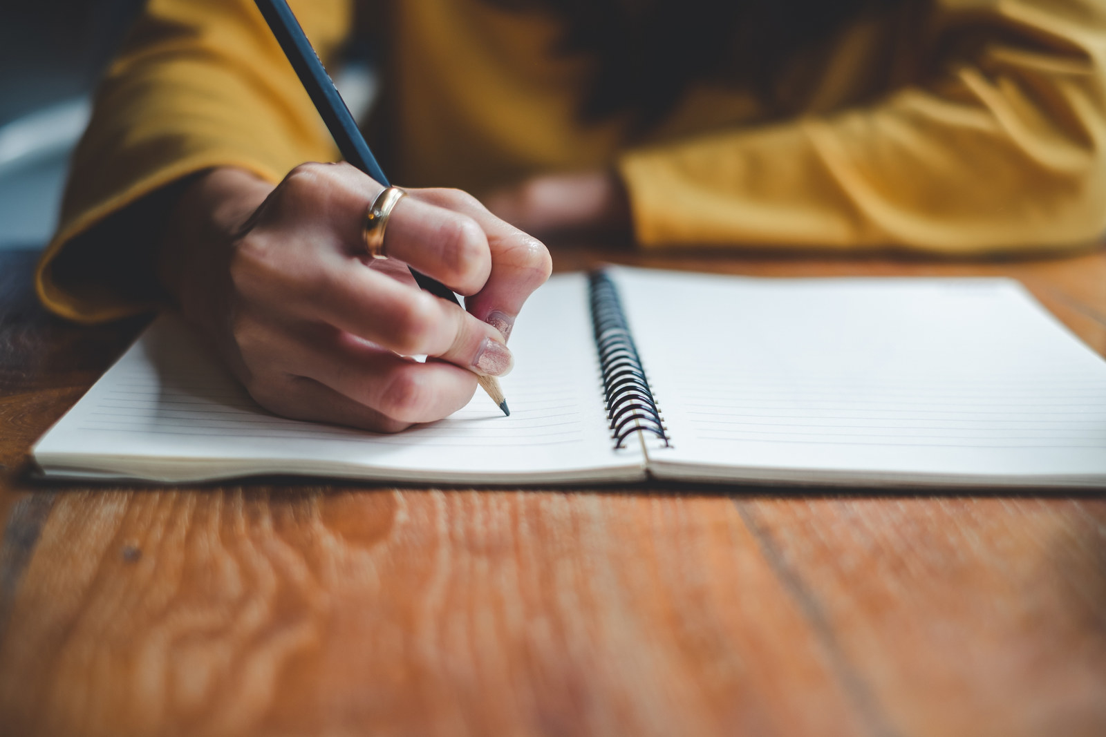 Woman&#x27;s hand holding a pencil about to write in a notebook
