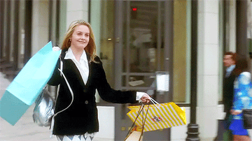 Gif of Alicia Silverstone in the movie &quot;Clueless&quot; walking out of a store with a number of shopping bags in both hand