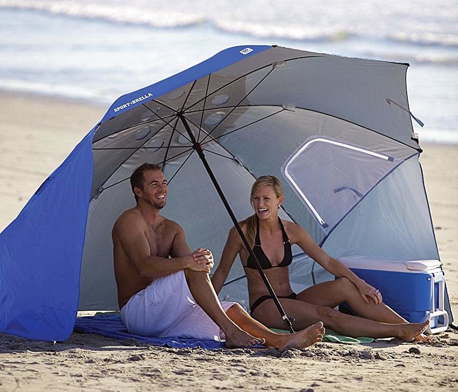 models on beach under big umbrella with two staked-down side flaps