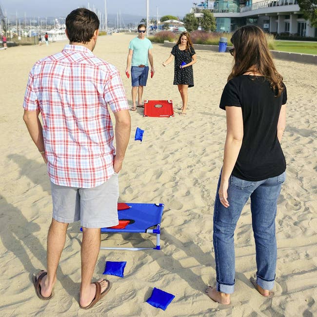 four people playing cornhole at the beach
