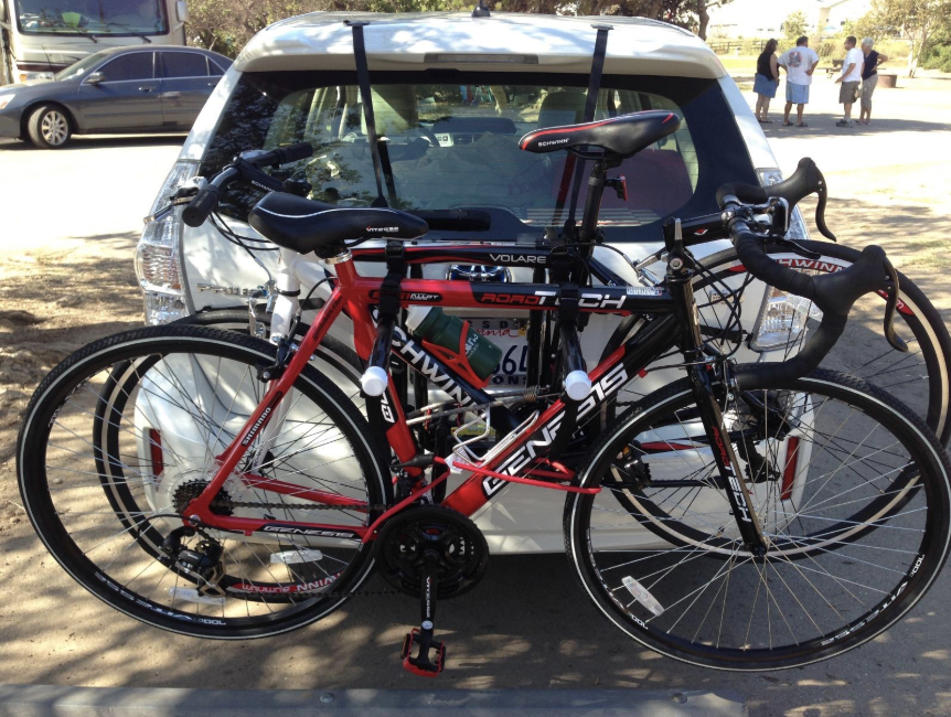 The back of a car holding up two bicycles using the rack