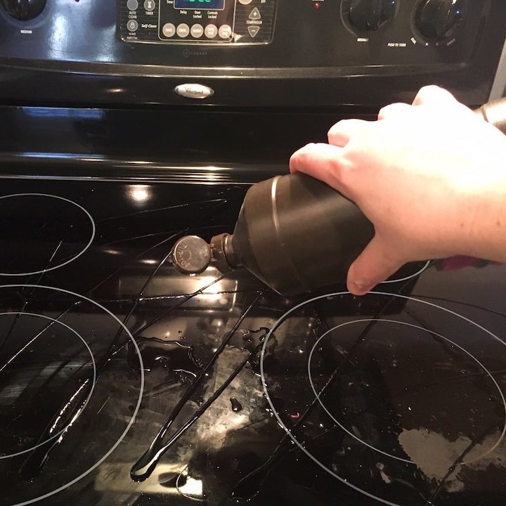 blogger's hand drizzling hydrogen peroxide over glass cooktop