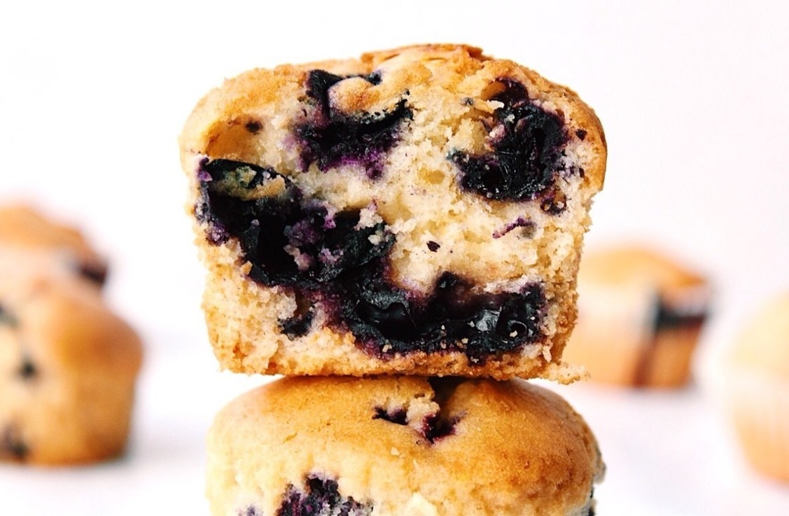 Close-up of a stacked blueberry muffin with a moist, fluffy texture and visible blueberries throughout