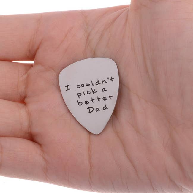 A hand holding the guitar pick that reads: I couldn't pick a better dad
