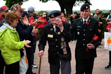 Richard Brown (center), a Canadian veteran of the World War II Battle of Normandy, departs with his son Andy to the applause of visitors following a commemorative ceremony in Normandy on June 5.
