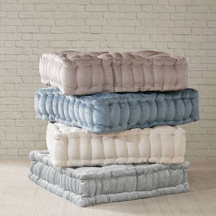 four square tufted floor pillows stacked on top of each other