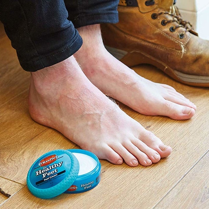 A jar of the foot cream next to some feet