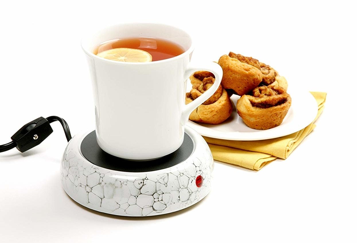 a mug on the mug warmer next to a small plate of pastries