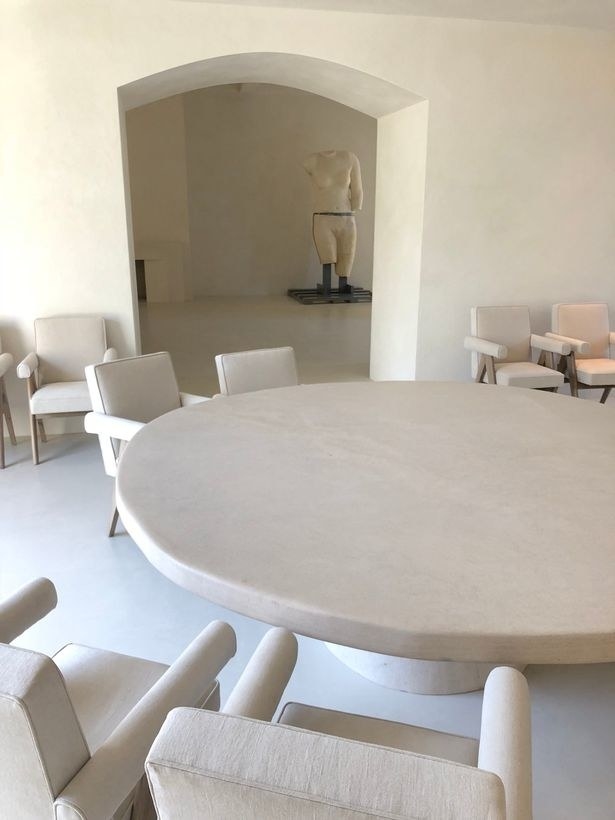 Very minimalist table and chairs with a creepy statue in the back