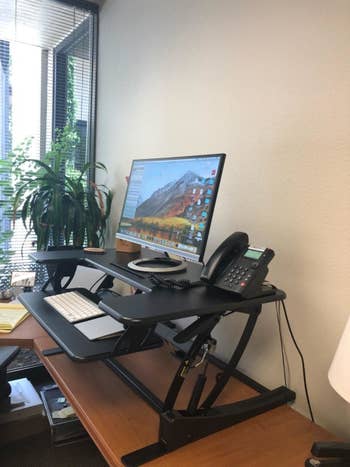 Same reviewer's photo of their desk but it's lifted, allowing them to work standing