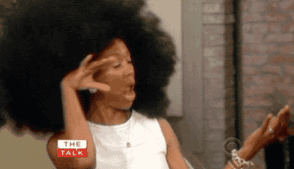 Gif of woman with afro proudly flipping it 
